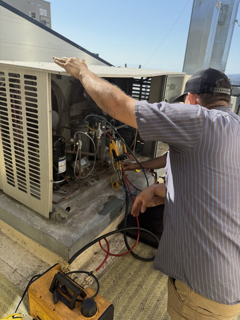 East Bay Refrigeration technician servicing an outdoor condensing unit with gauges attached