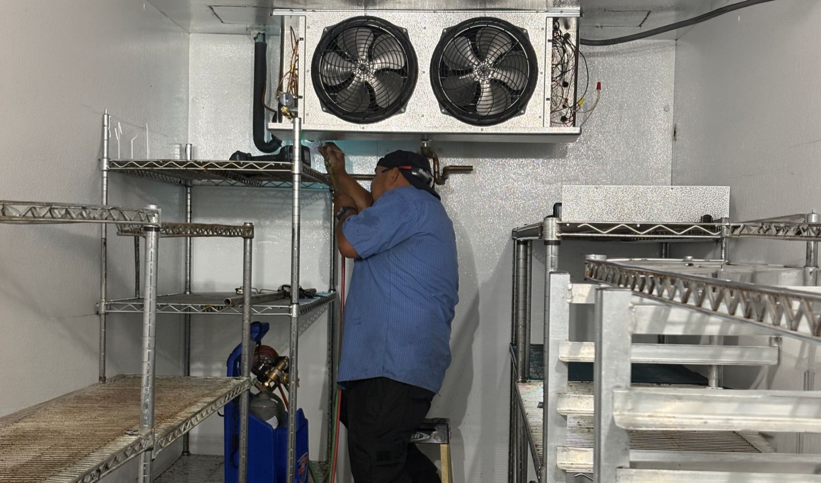 Technician servicing a walk-in cooler evaporator